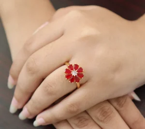 Gold-toned floral ring with red zircon petals and clear zircon centerpiece.