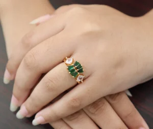 Gold-toned ring with alternating green rectangular and clear square zircon stones.