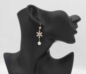 Gold-toned snowflake earrings with zircon stones and a dangling pearl, crafted from stainless steel.