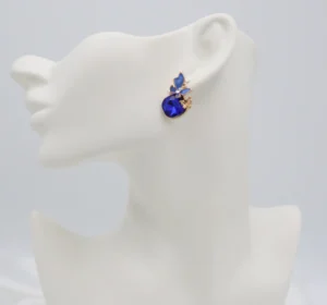 Gold-toned stud earrings with a deep sapphire-blue stone and butterfly motif, accented with small crystals.