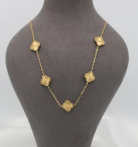 Gold-toned pendant set featuring four-leaf clover charms with smooth enamel-like inlays.