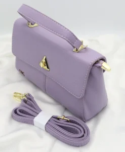 Light purple faux leather handbag with gold-tone hardware, flap lock closure, and compact rectangular shape.